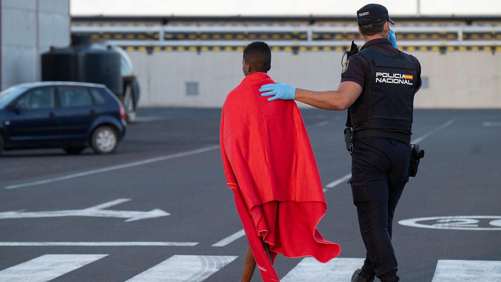 Un policía acompaña a una persona migrante tras su llegada a Puerto del Rosario, Fuerteventura
