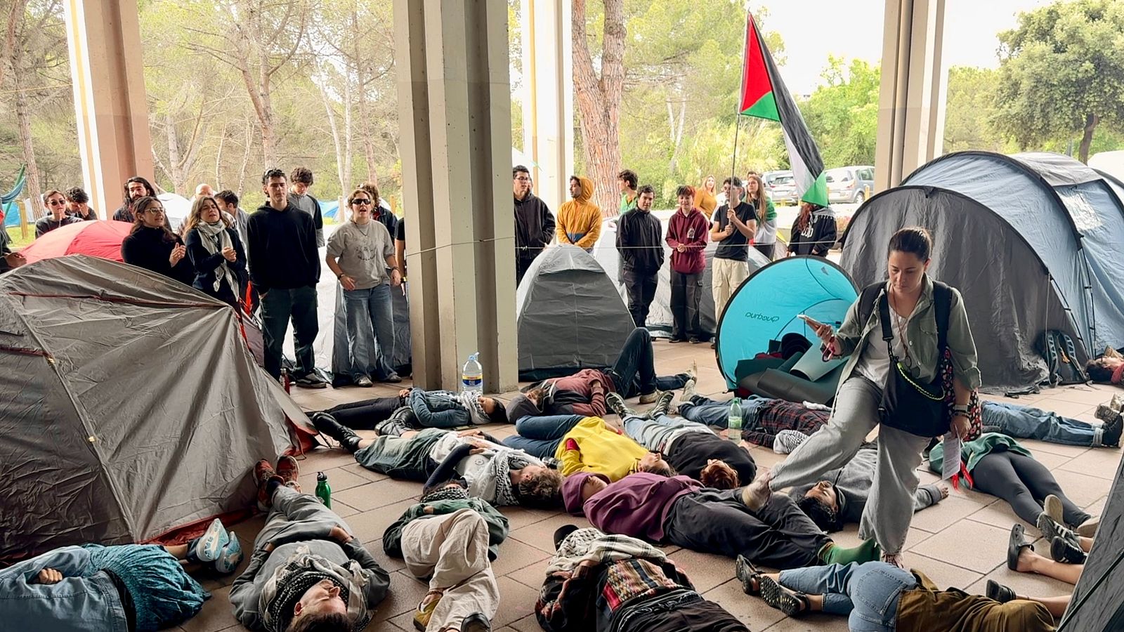 Una dona passa entre les persones estirades a terra en la protesta davant del Rectorat de la UAB. | ACN : Albert Segura
