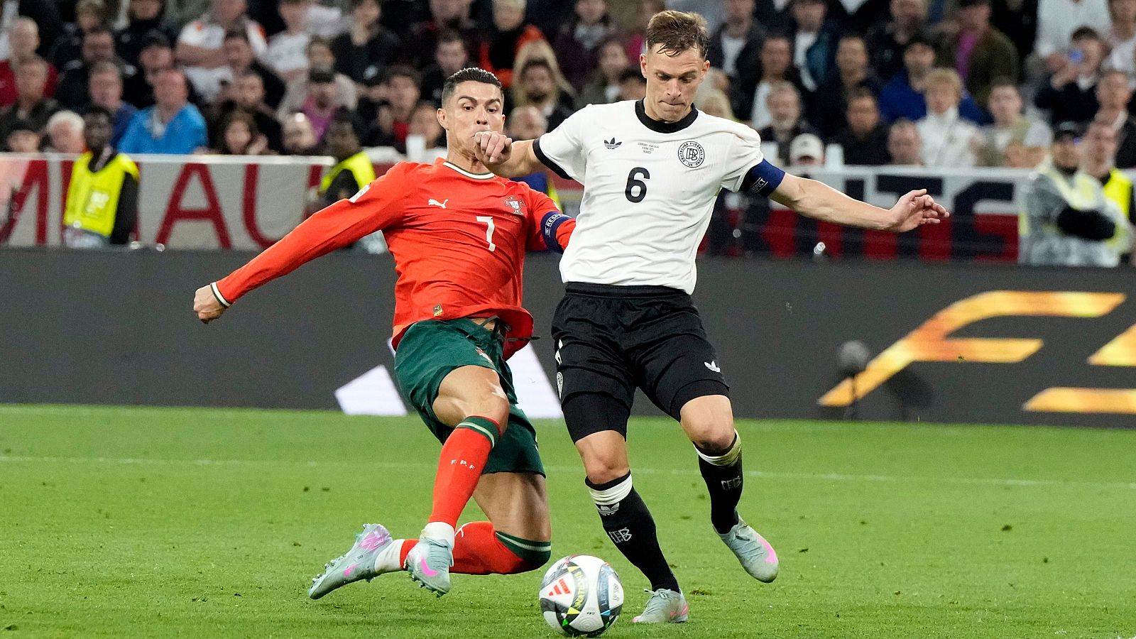 Intenso momento de un partido de fútbol: Cristiano Ronaldo (Portugal) intenta un disparo mientras Joshua Kimmich (Alemania) lo defiende.