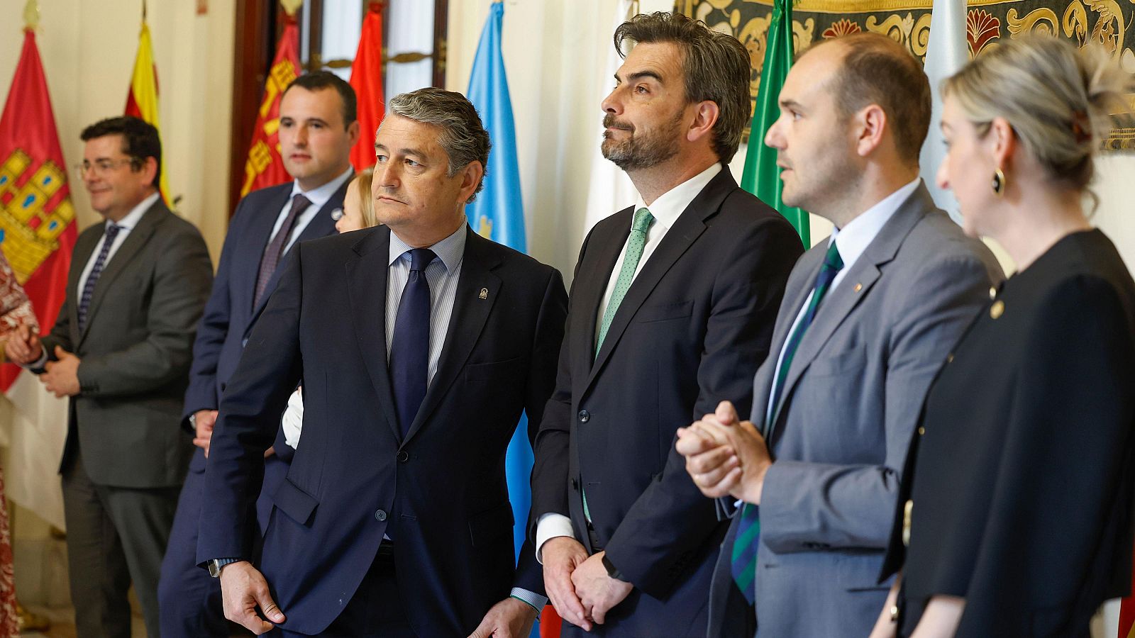 Consejeros autonómicos en comité preparatorio para la Conferencia de Presidentes.  Banderas de España y comunidades presentes. Conversación informal previa a la reunión.