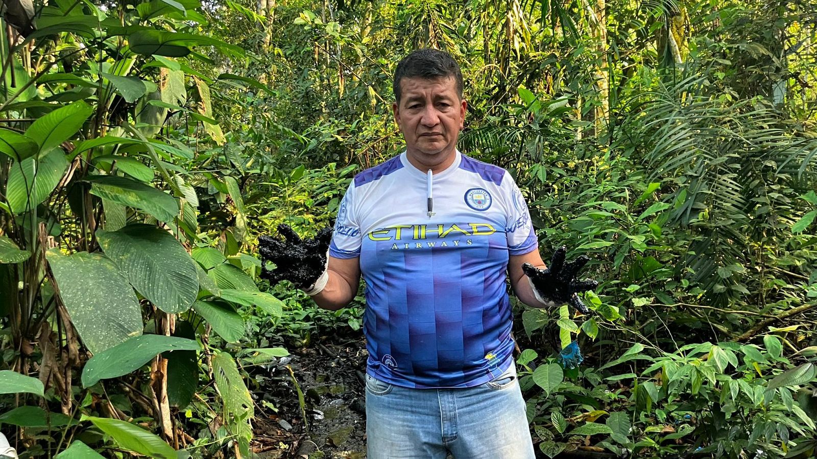 Presidente de la UDAPT con manos manchadas de petróleo de una piscina abandonada en la Amazonía.  Imagen que documenta la contaminación petrolera.