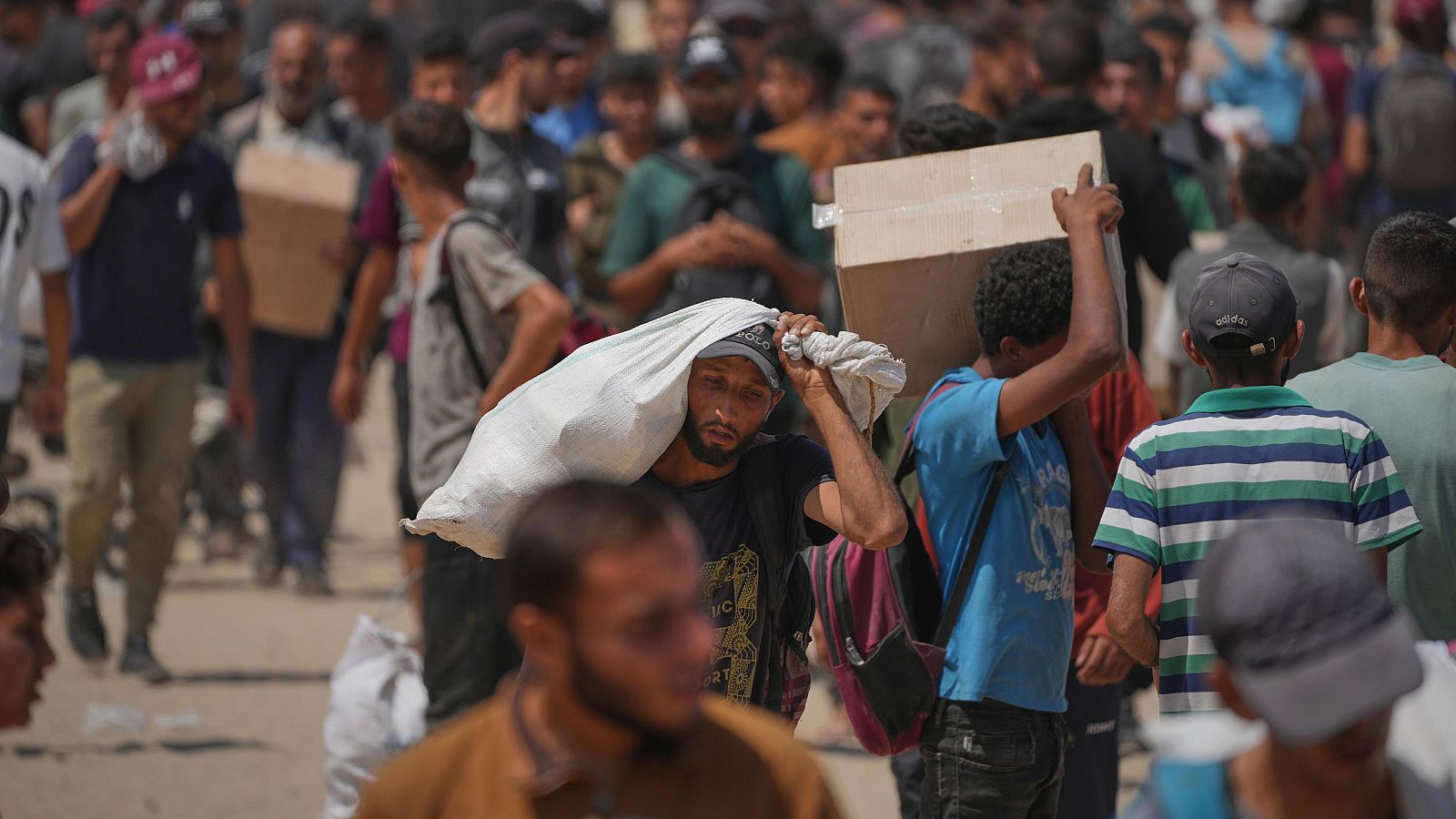Hombres palestinos transportan alimentos en cajas y bolsas