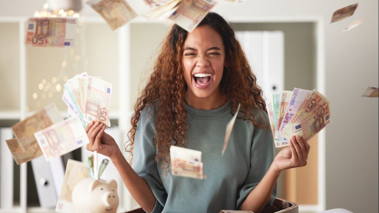 Mujer joven, cabello rizado, celebra con billetes de euro.  Abundancia y euforia.  Se observa una hucha.