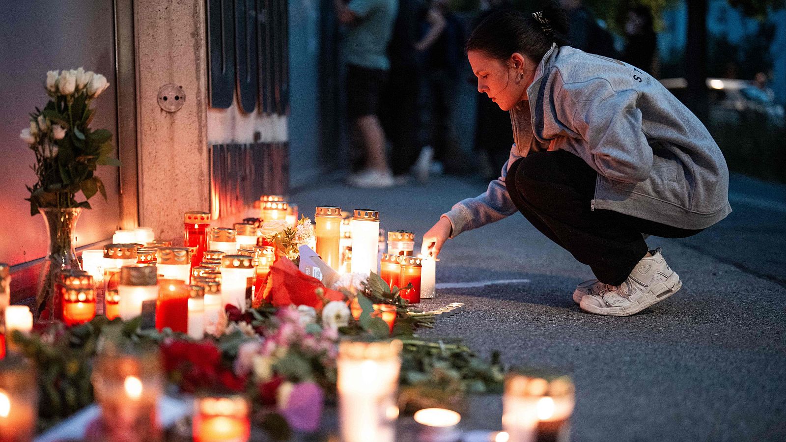 Una mujer deja una vela cerca de la escuela donde varias personas murieron en un tiroteo en Graz, Austria
