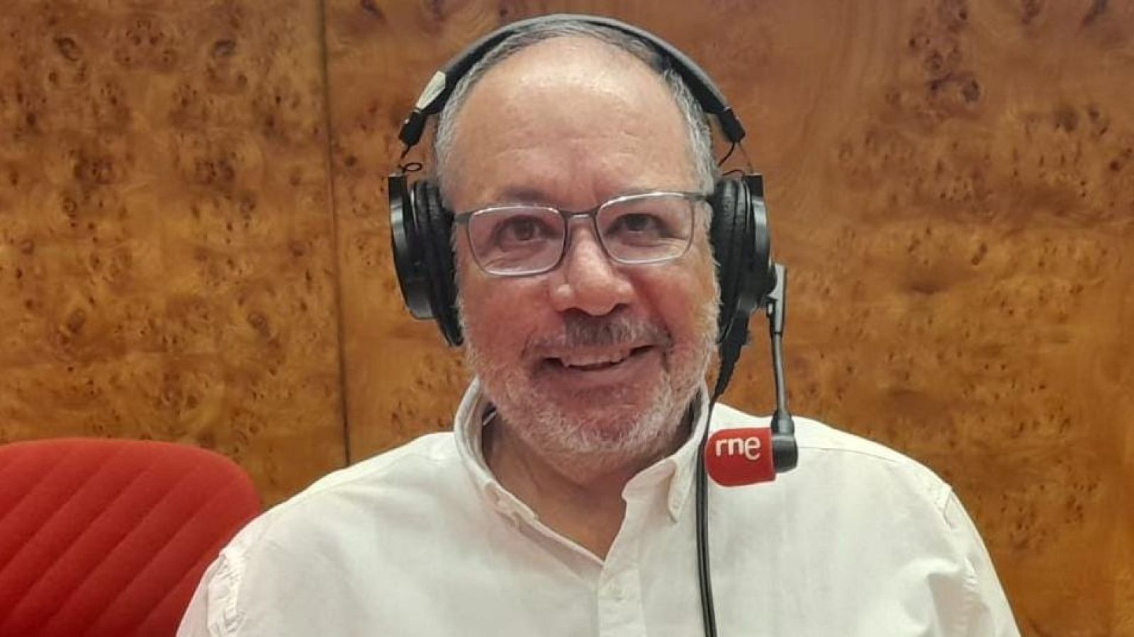 Periodista con gafas y auriculares en estudio de radio, posiblemente RNE, participando en un programa cultural.