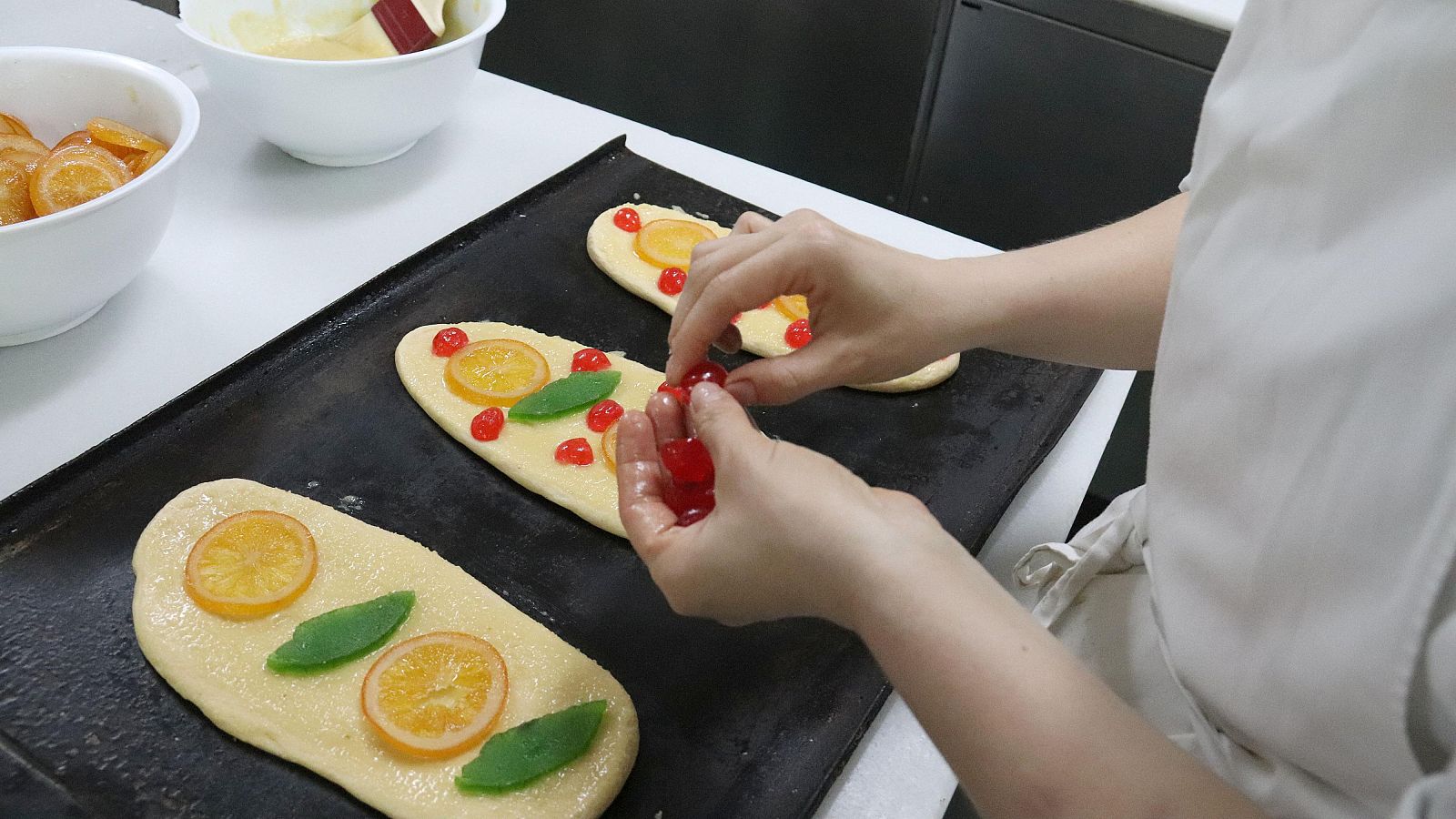Una pastissera posa fruita confitada a les coques de Sant Joan en preparació. Aina Martí/ACN
