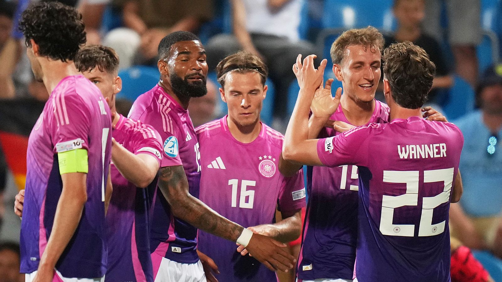 Celebración de jugadores alemanes sub-21 con camisetas rosas tras un gol o victoria.  Dorsales visibles: 10, 13, 16 y 22 (Wanner).