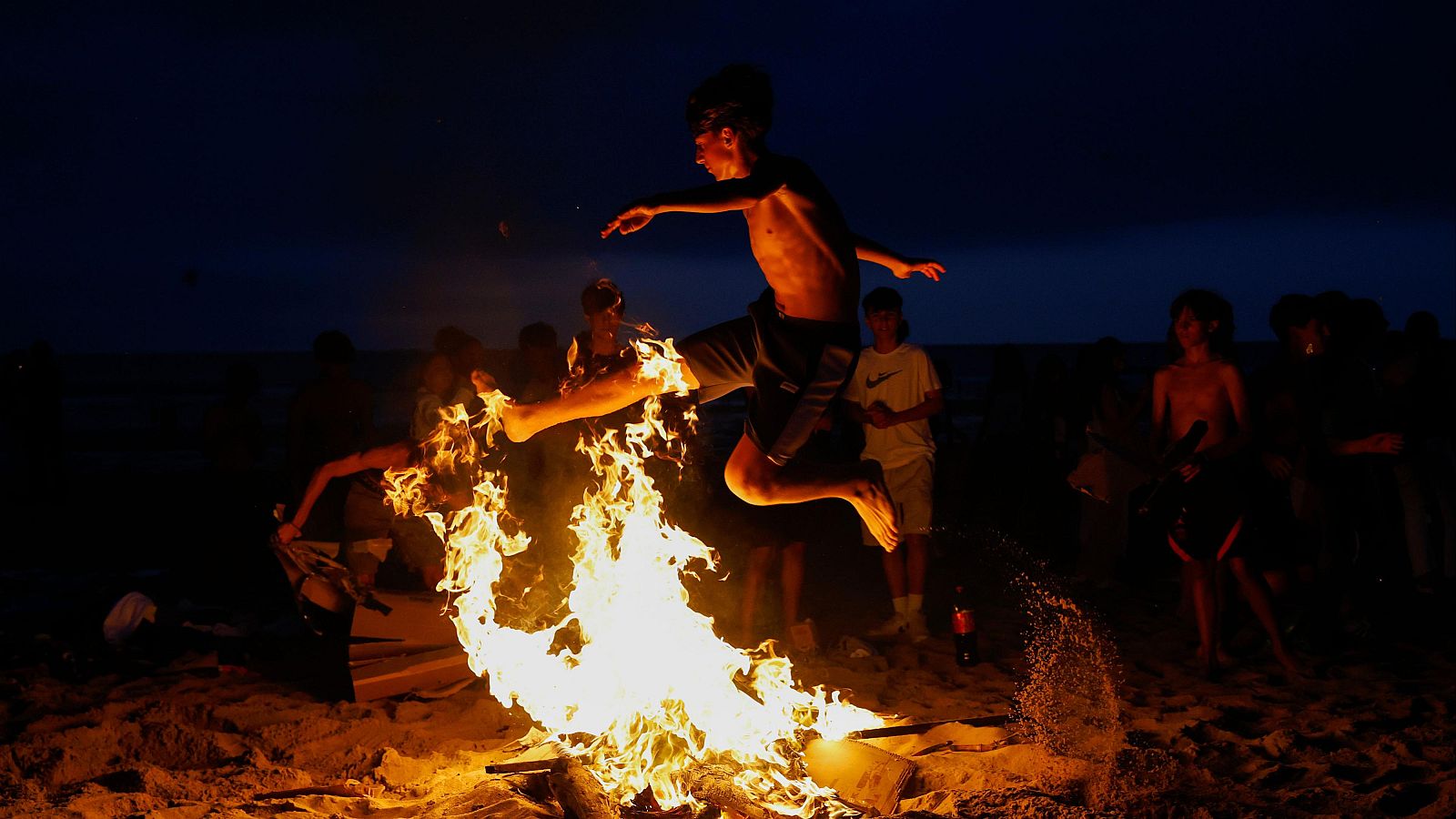 Una persona salta una hoguera durante la celebración de la noche de San Juan en San Sebastián