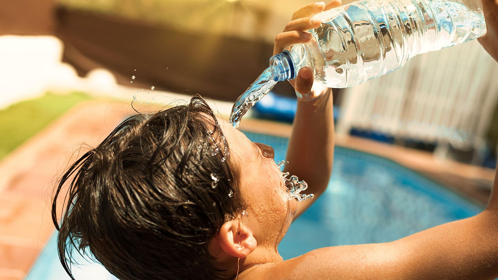 Un niño se refresca echándose agua en la cara ante el exceso de calor