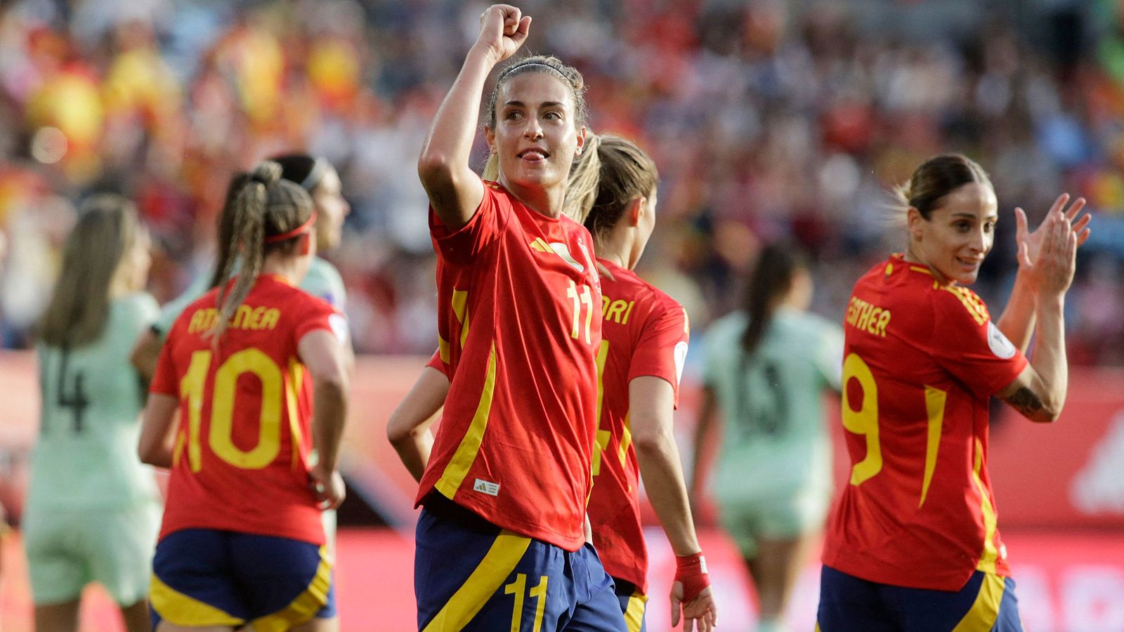 Alexia Putellas, con la camiseta roja número 11, celebra un gol con euforia y el puño levantado, acompañada de otras jugadoras españolas.