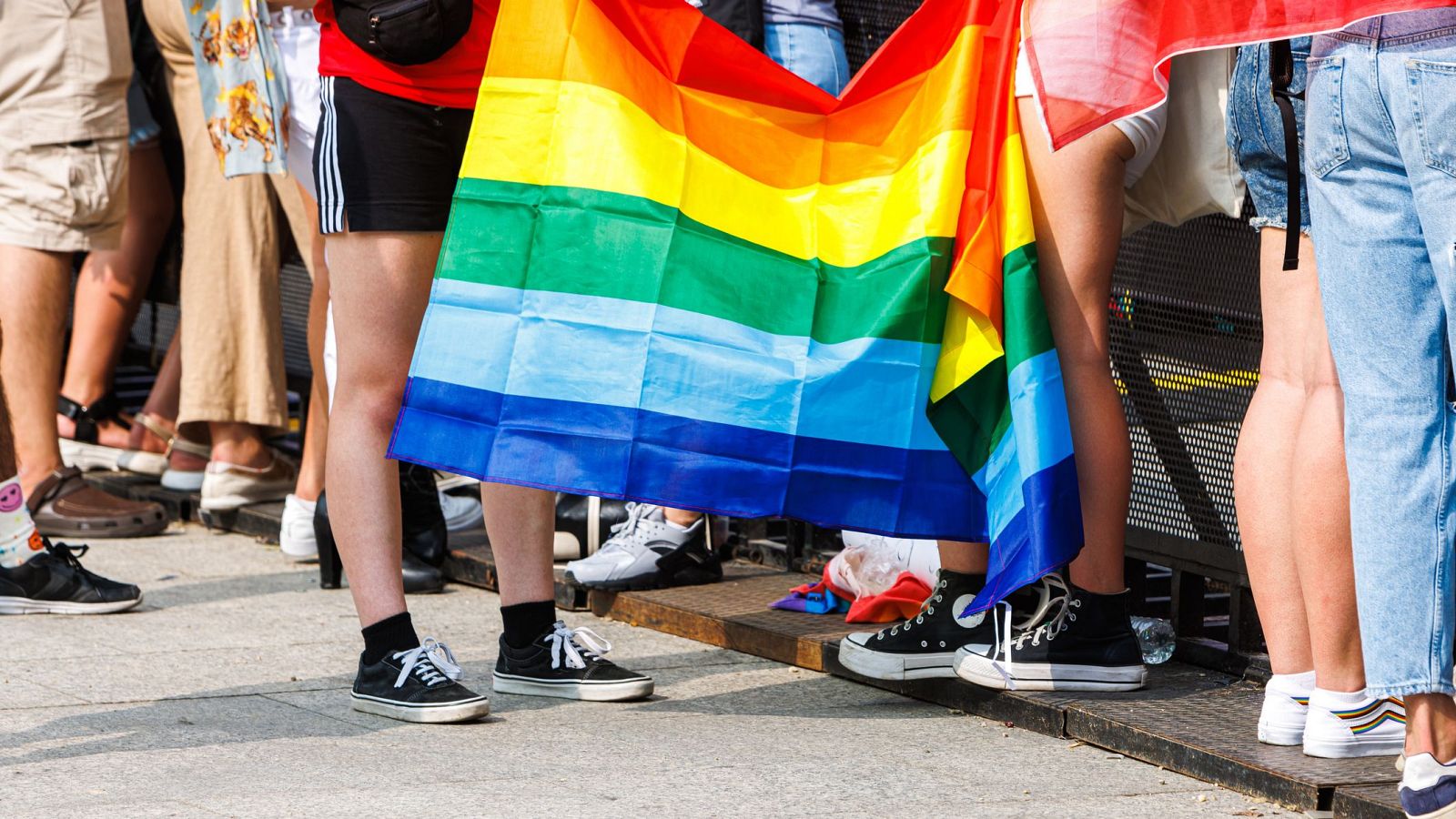 Un grupo de personas sujetan una bandera arcoíris en una celebración del Orgullo LGTBIQ+.
