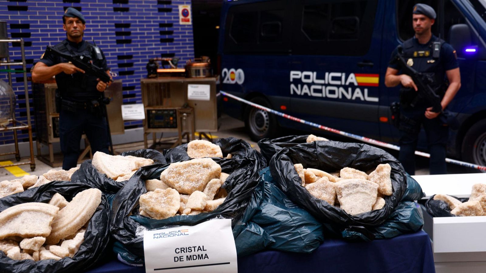 Dos agentes de Policia armados, protegen la droga sintética incautada en el mayor laboratorio desmantelado en España