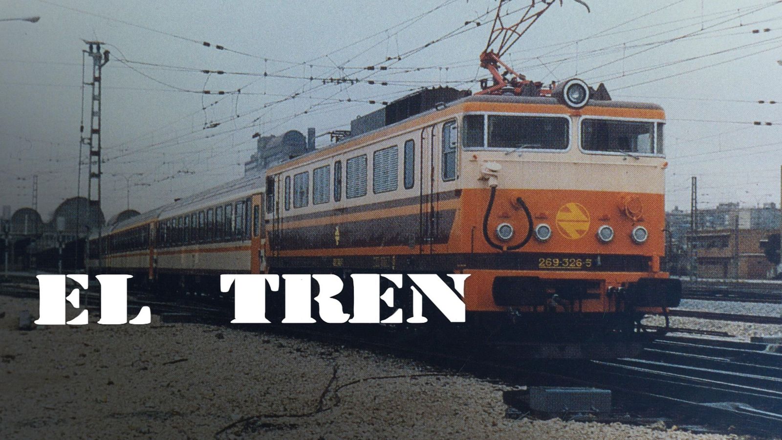 Locomotora de tren naranja y marrón, número de serie visible, vagones de pasajeros y parte de una estación al fondo. Texto "EL TREN" en la parte inferior.