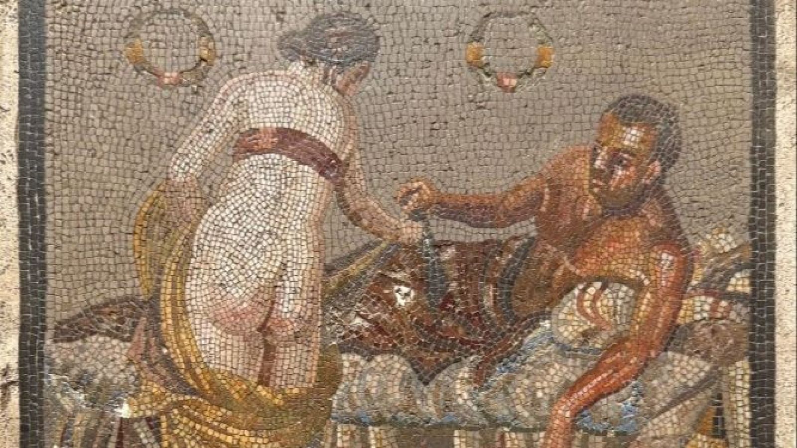 Mosaico romano erótico (siglo I a.C.) con dos figuras: un hombre recostado y una mujer con vestido dorado y banda roja. Recuperación tras robo en la II Guerra Mundial.