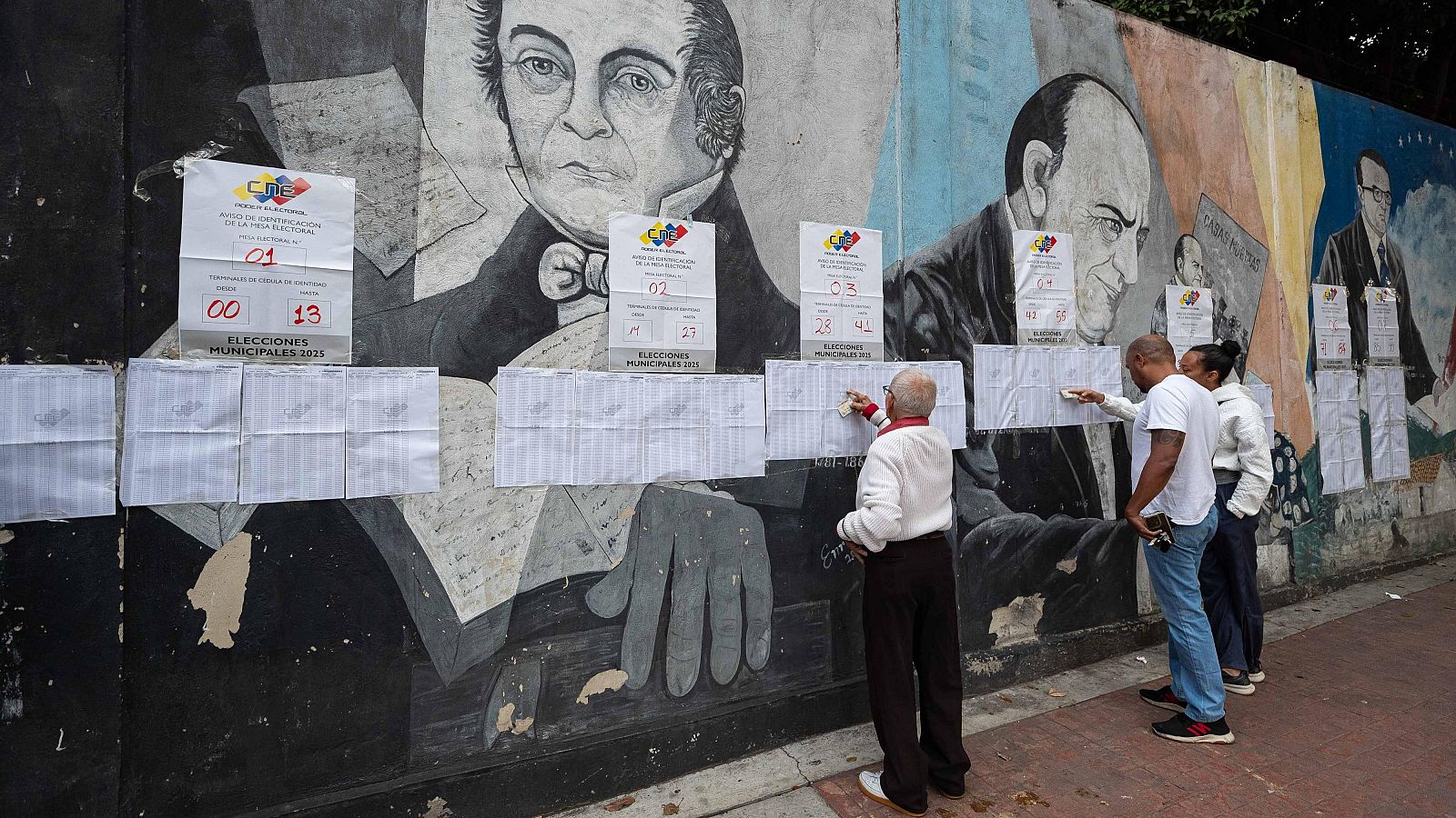 Varias personas observan las listas en un centro electoral en Caracas, este domingo.