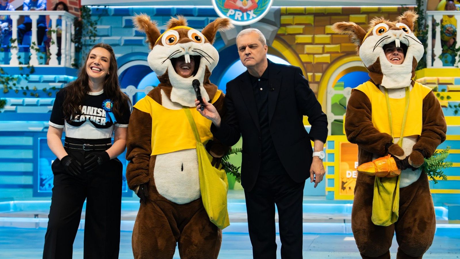 Inés Hernand en el Grand Prix con camiseta negra "Spanish Leather", junto a Ramón García y dos ardillas (una con micrófono, otra con zanahoria) en un escenario de castillo.