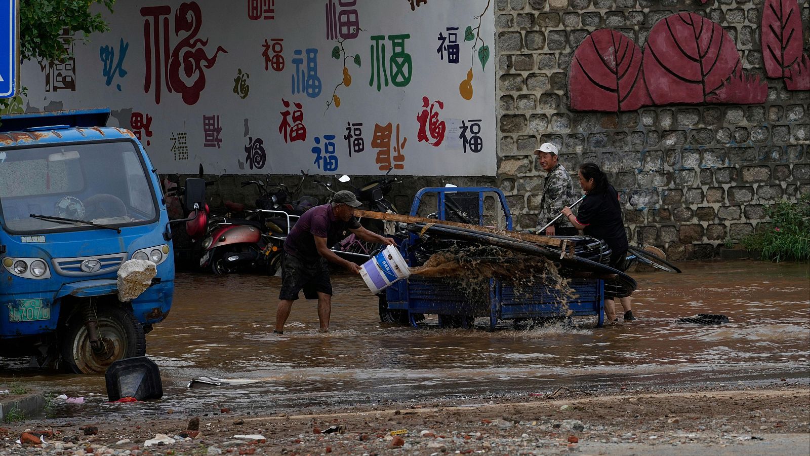 Personas limpian su vehículo en aguas inundadas tras fuertes lluvias en la localidad de Taishitun, distrito de Miyun, en las afueras de Pekín, China