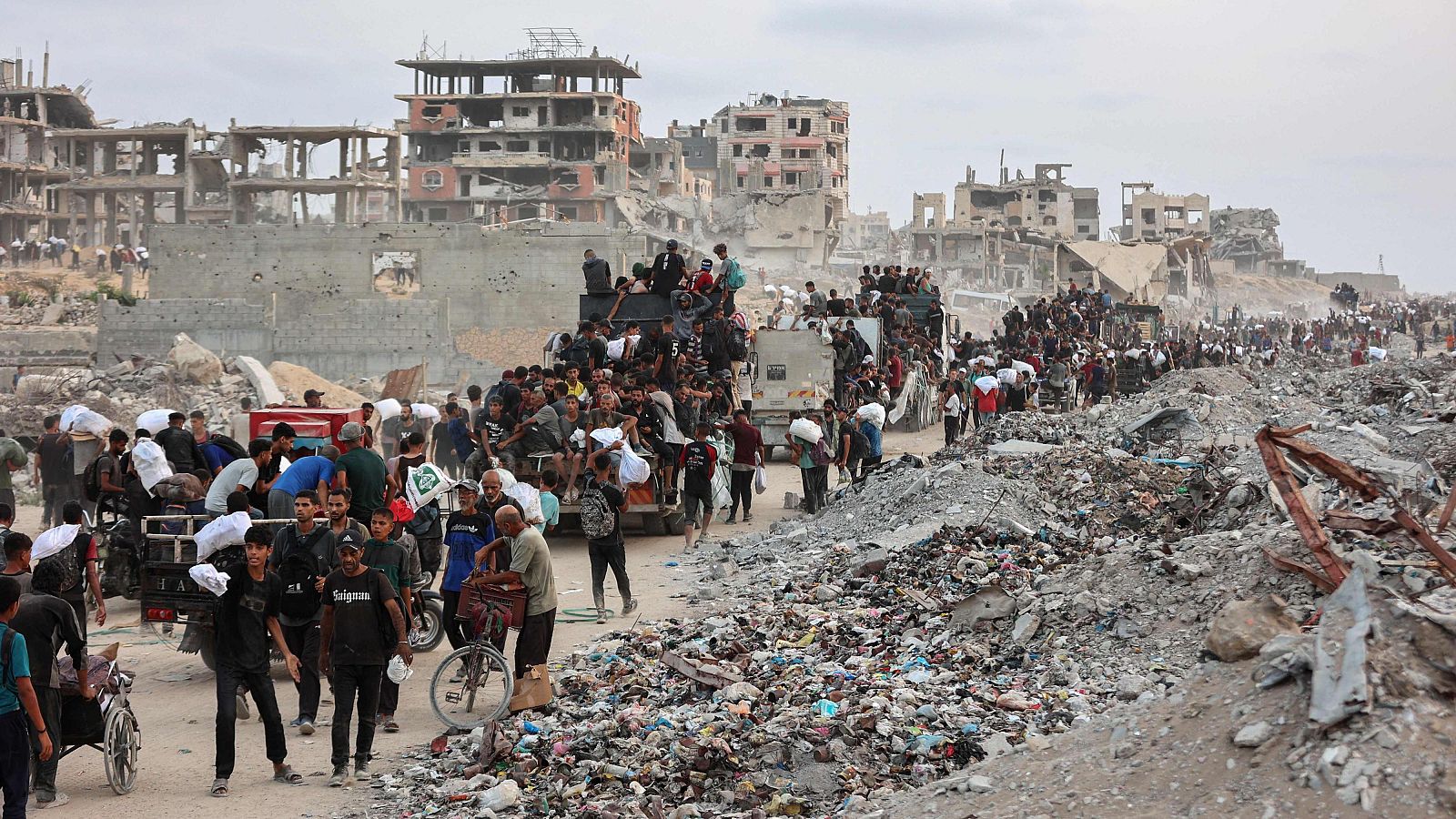 Palestinos regresan con paquetes de ayuda que lograron conseguir mientras caminan por un sendero costero al oeste de Beit Lahia