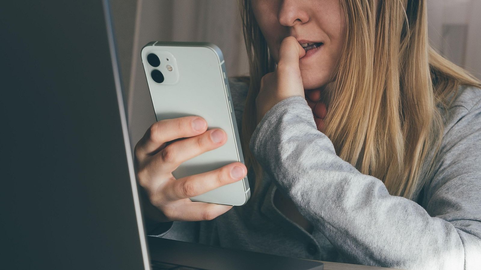 Una mujer mira nerviosa su teléfono móvil