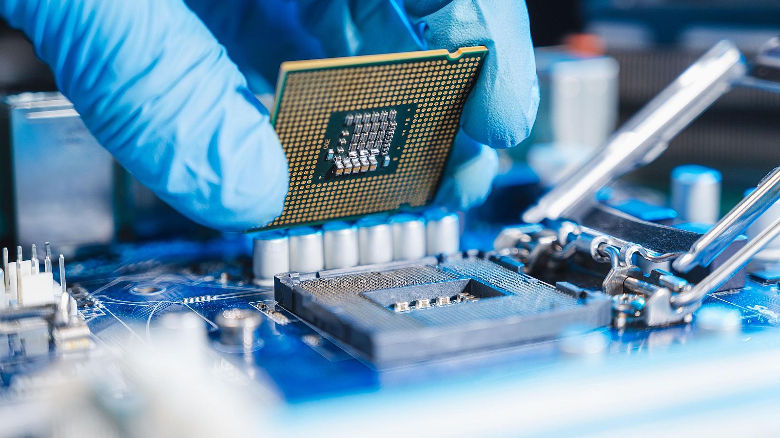 Mano enguantada instala un microprocesador en una placa base azul.  Representación visual del ensamblaje de componentes electrónicos.