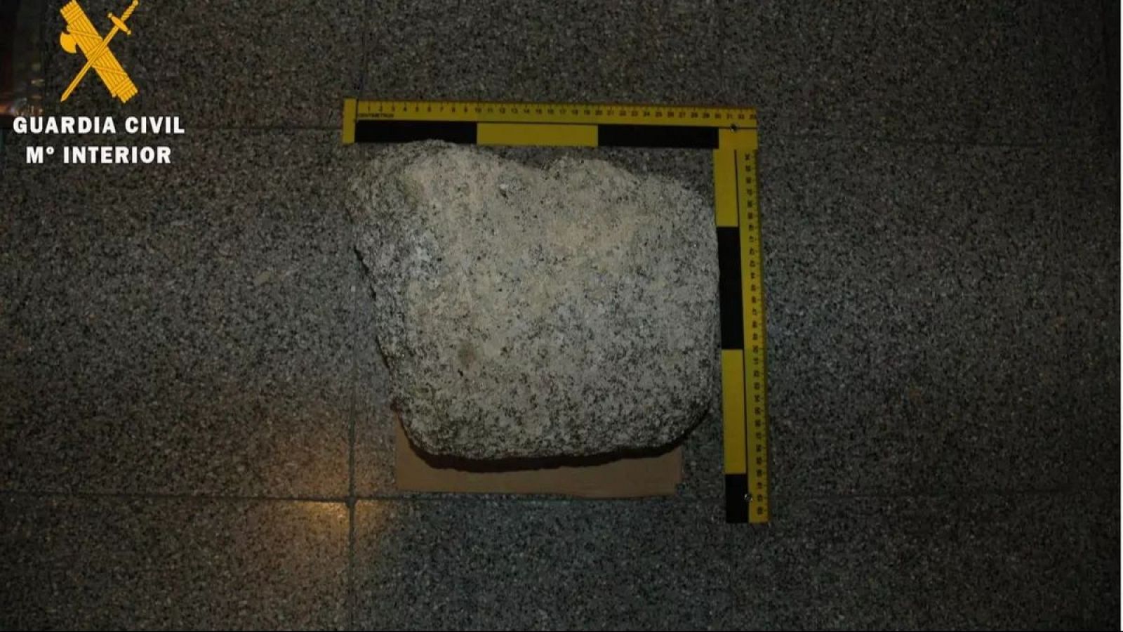 Piedra gris rugosa sobre cartón, medida con regla amarilla y negra.  En la esquina superior izquierda se lee "GUARDIA CIVIL" y "Mº INTERIOR".