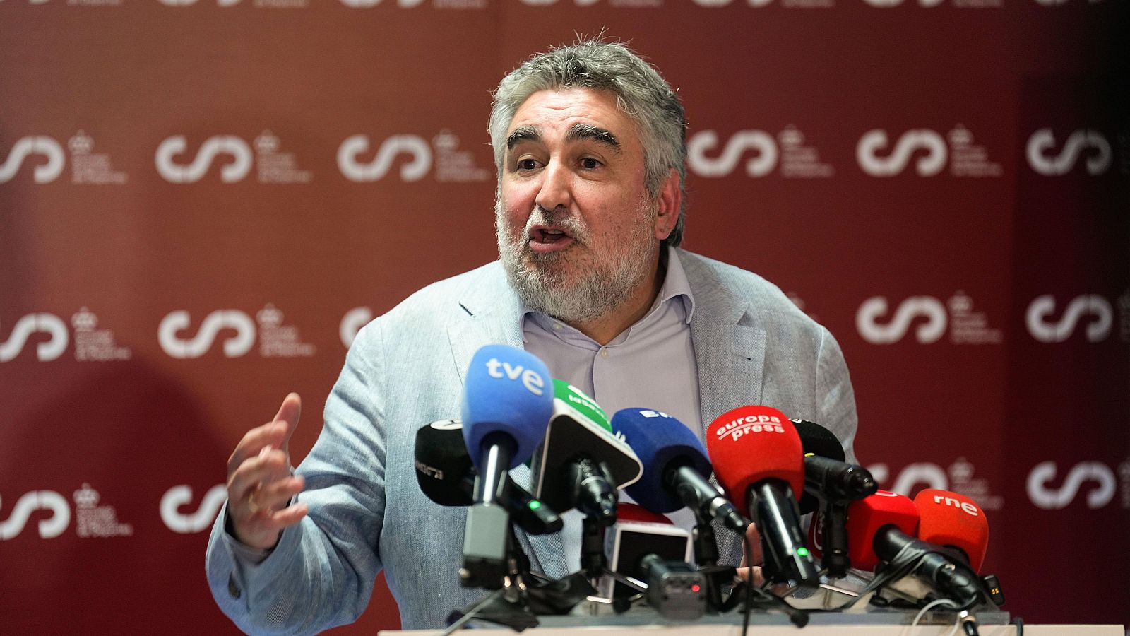 Rueda de prensa del presidente del CSD. Gestos mientras habla a micrófonos de medios de comunicación. Logo del CSD de fondo.