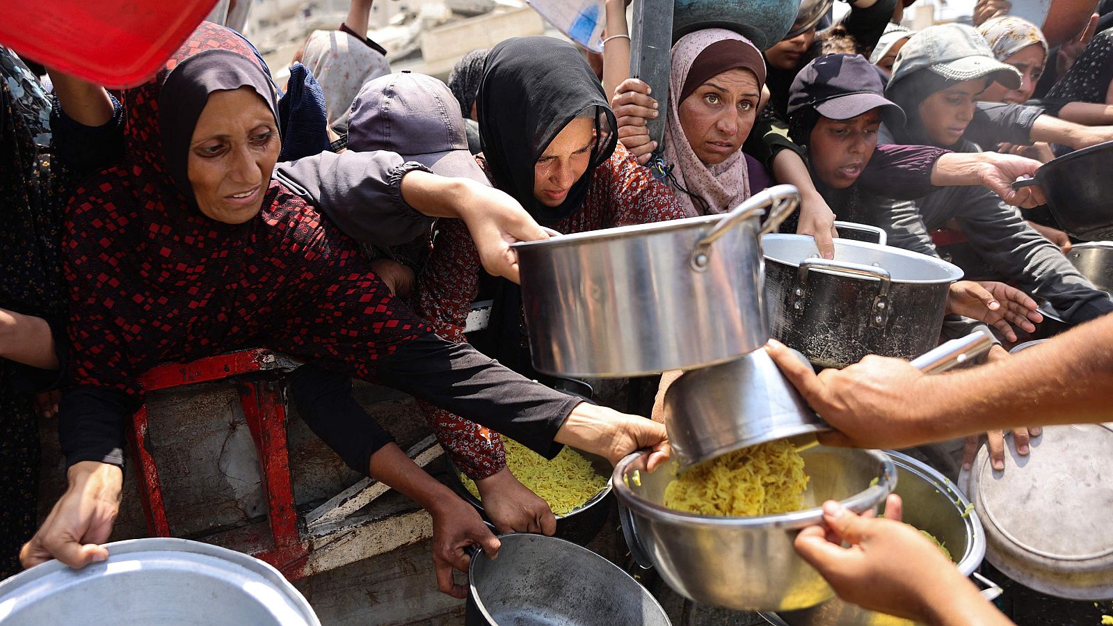 Palestinos reciben comida preparada de un centro de distribución de alimentos en la ciudad de Gaza
