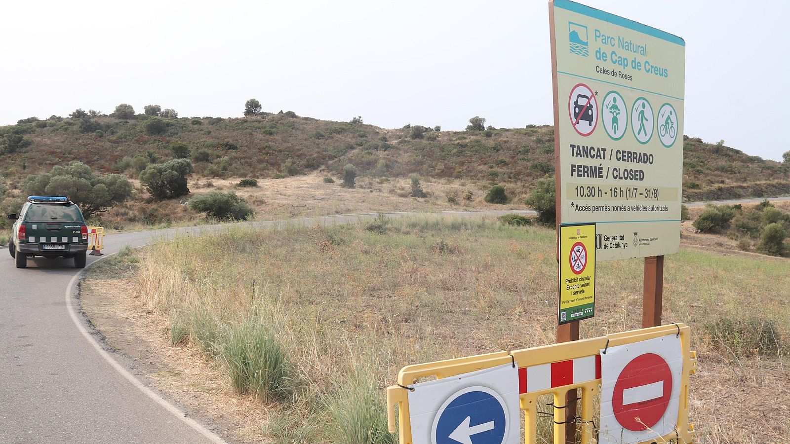 El cotxe dels Agents Rurals al fons i en primer terme un cartell que anuncia algunes restriccions de circulació al Parc Natural del Cap de Creus