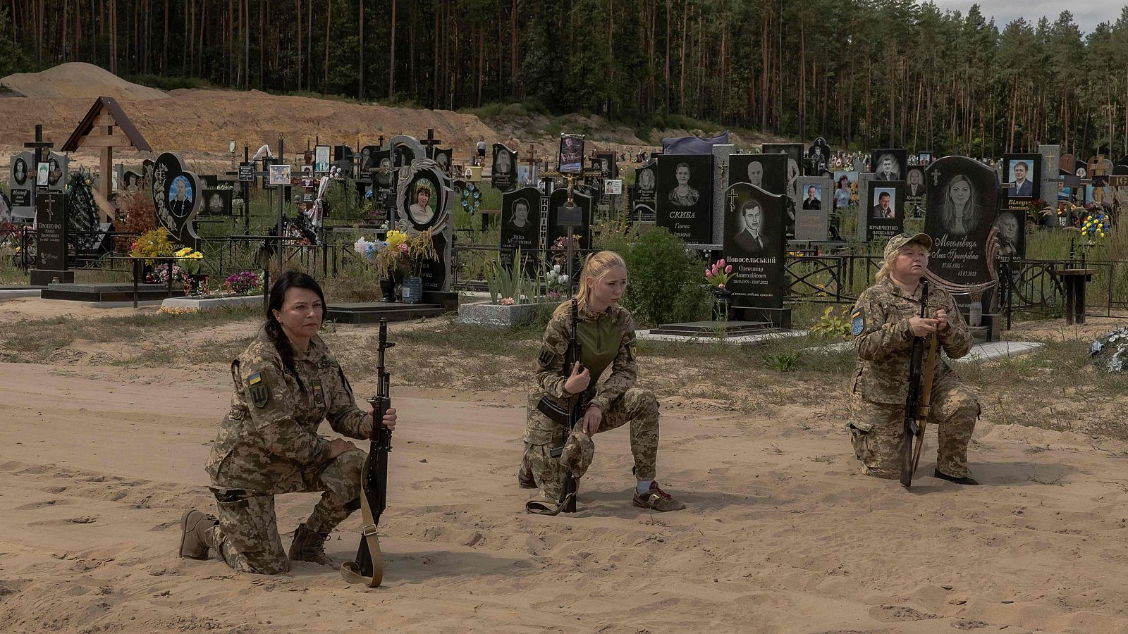 Soldados ucranianas se arrodillan durante una ceremonia fúnebre por una compañera que murió en un bombardeo de artillería