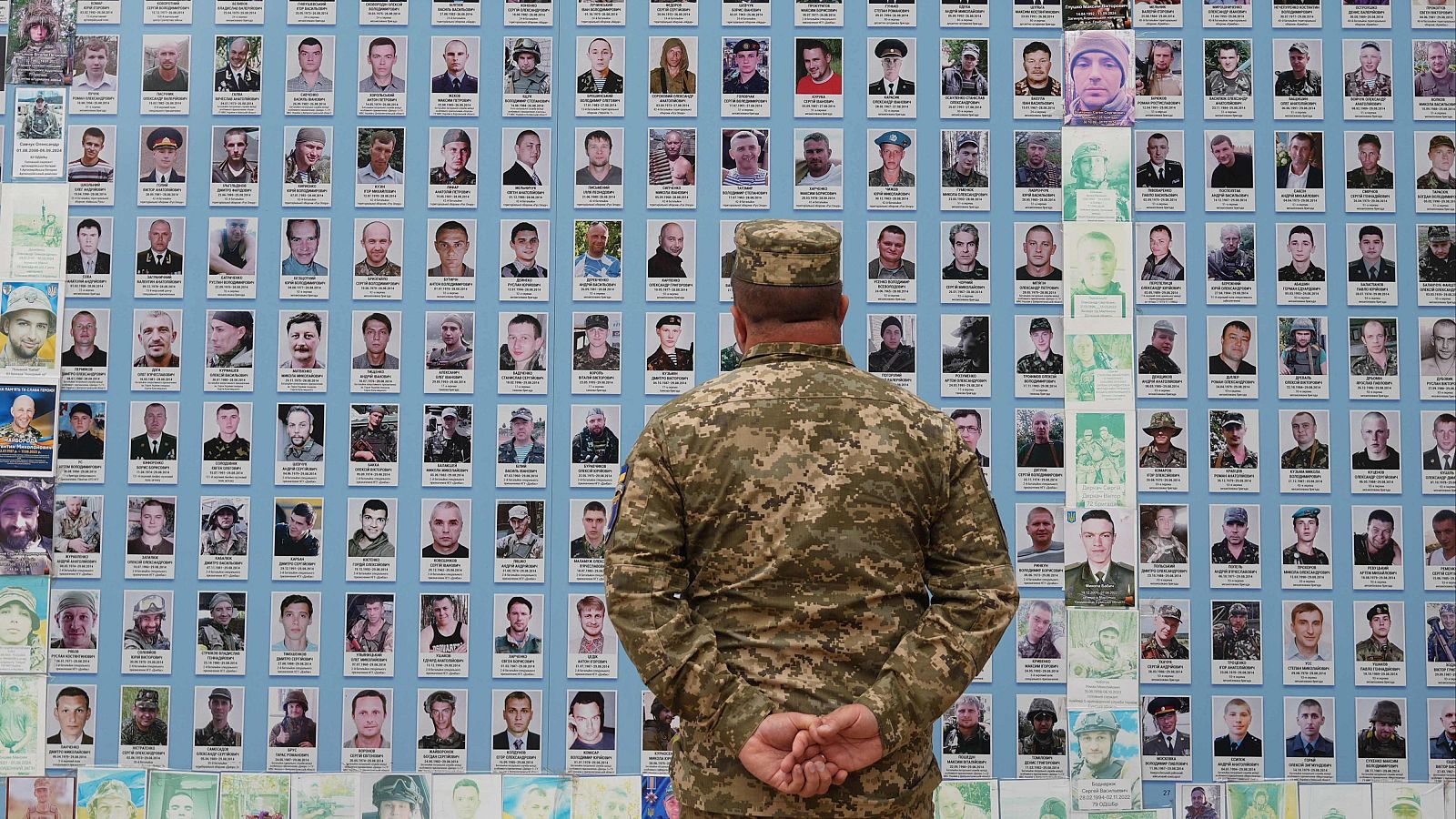 Un soldado observa fotos de camaradas muertos en combate en el 'Muro del Recuerdo de los Caídos por Ucrania' en Kiev.