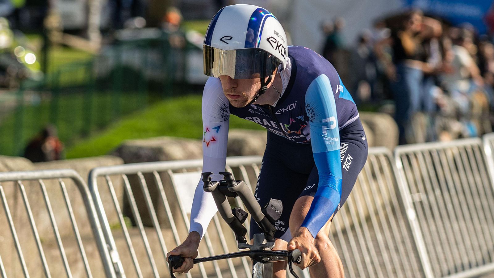 Ciclista en posición aerodinámica con maillot azul marino y celeste del equipo Israel - Premier Tech, mostrando la estrella de David. Casco EKOI.