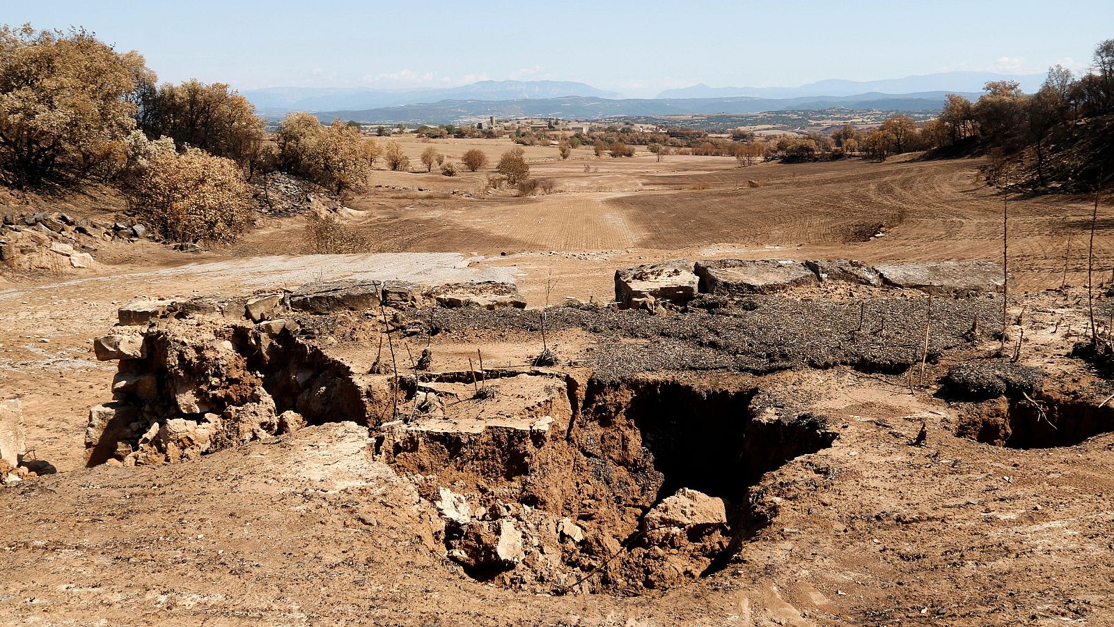 Derrumbe de pared de piedra seca tras el paso del agua. Gran agujero central.  Terreno seco y polvoriento.