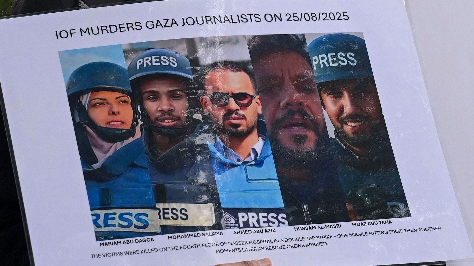 Una persona sostiene un cartel con fotos y nombres de periodistas palestinos muertos en los ataques israelíes al hospital Nasser el 25 de agosto