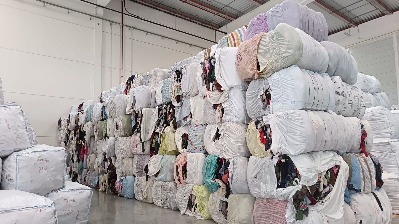 Paquetes de ropa usada para reciclar en un almacén de Moda Re-