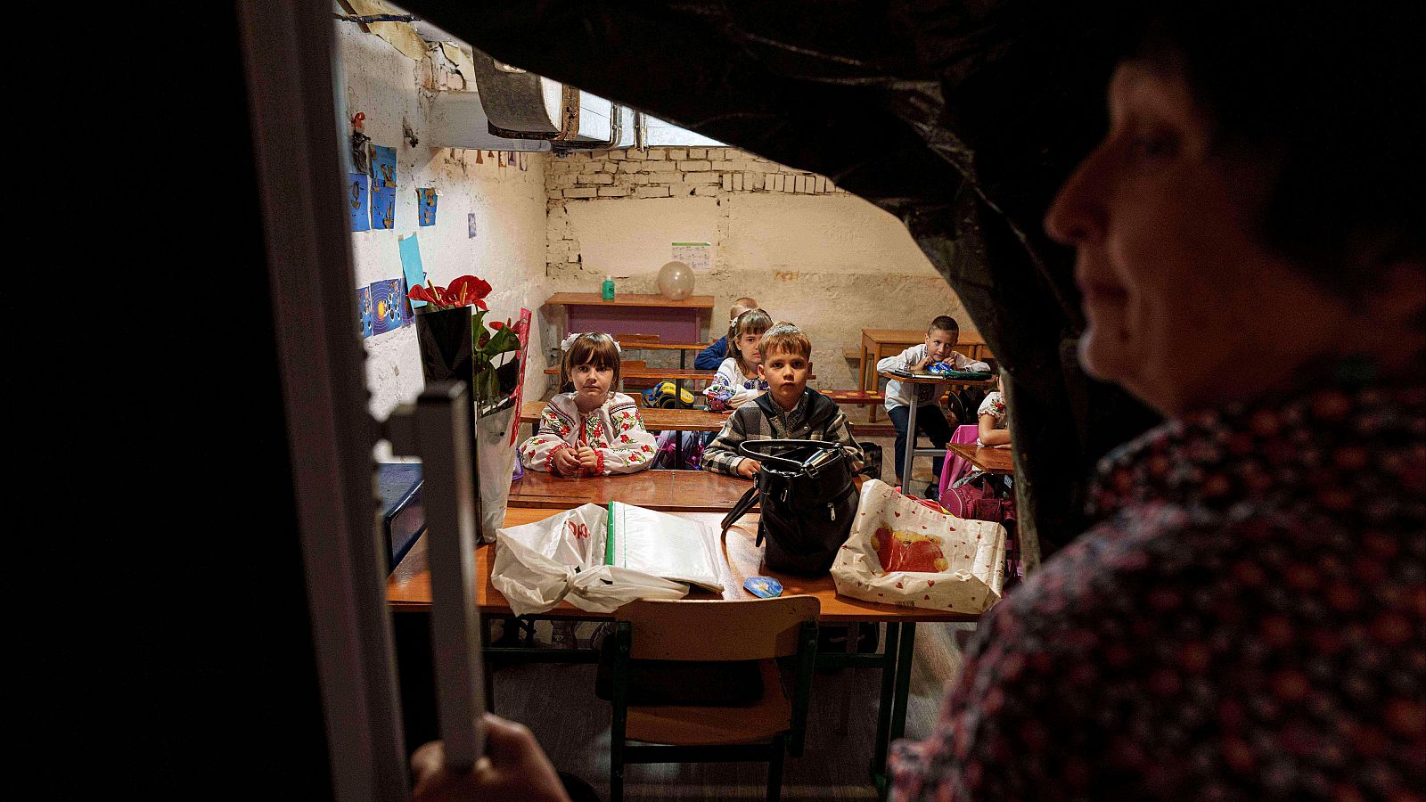 Estudiantes escuchan a su maestra durante en el sótano de un edificio municipal durante el primer día de clases en Bobryk