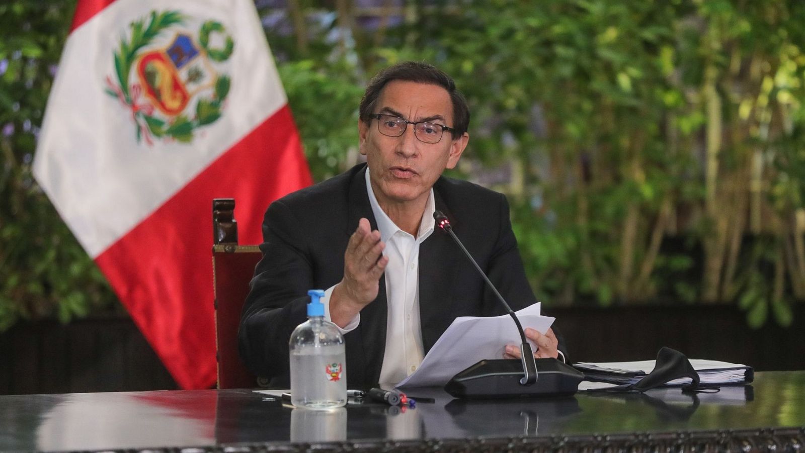 Imagen de archivo (2020) del expresidente peruano Martín Vizcarra en una declaración pública.  Viste camisa blanca y chaqueta oscura, gesticula con una mano mientras sostiene papeles; sobre la mesa hay gel hidroalcohólico y mascarilla.
