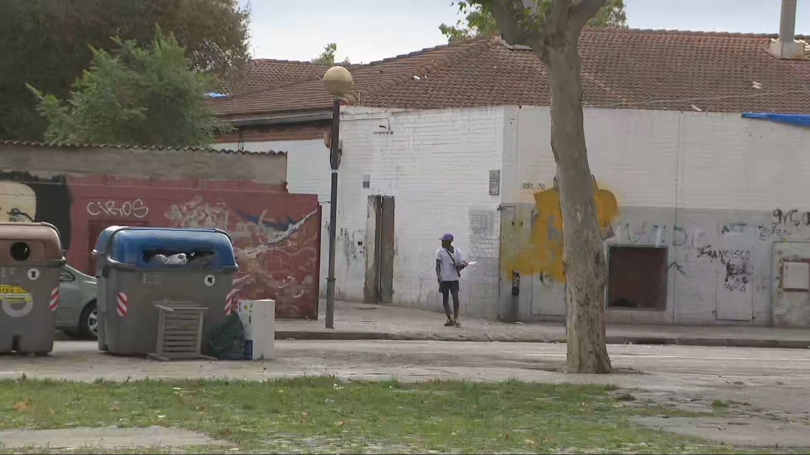 Antic edifici, possiblement un institut, amb deteriorament visible, pintades i una persona caminant al davant.  