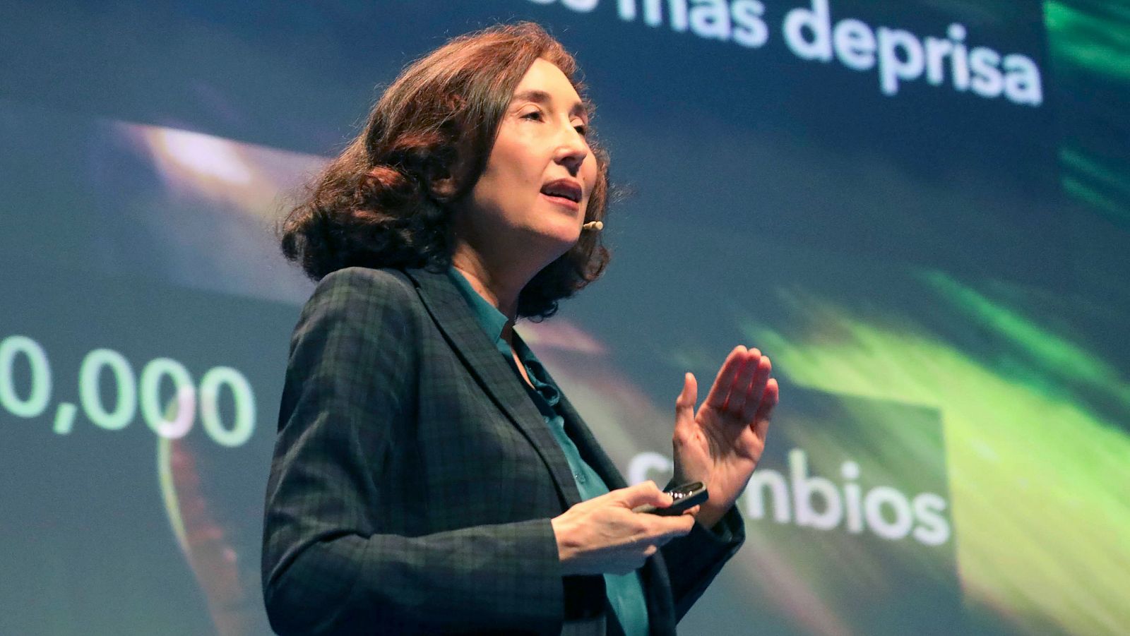 Elsa Punset presenta, gesticulando y sosteniendo un objeto pequeño.  La pantalla muestra gráficos y texto parcialmente visible: '...más deprisa' y '...mbios', además de '0,000'.