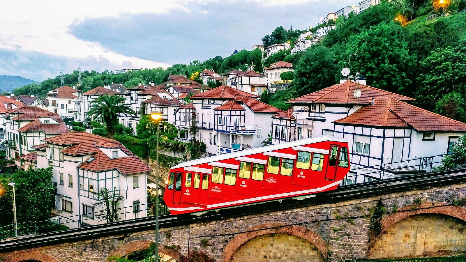 Funicular rojo de Artxanda subiendo entre casas con tejados rojos hacia la cima del monte en Bilbao