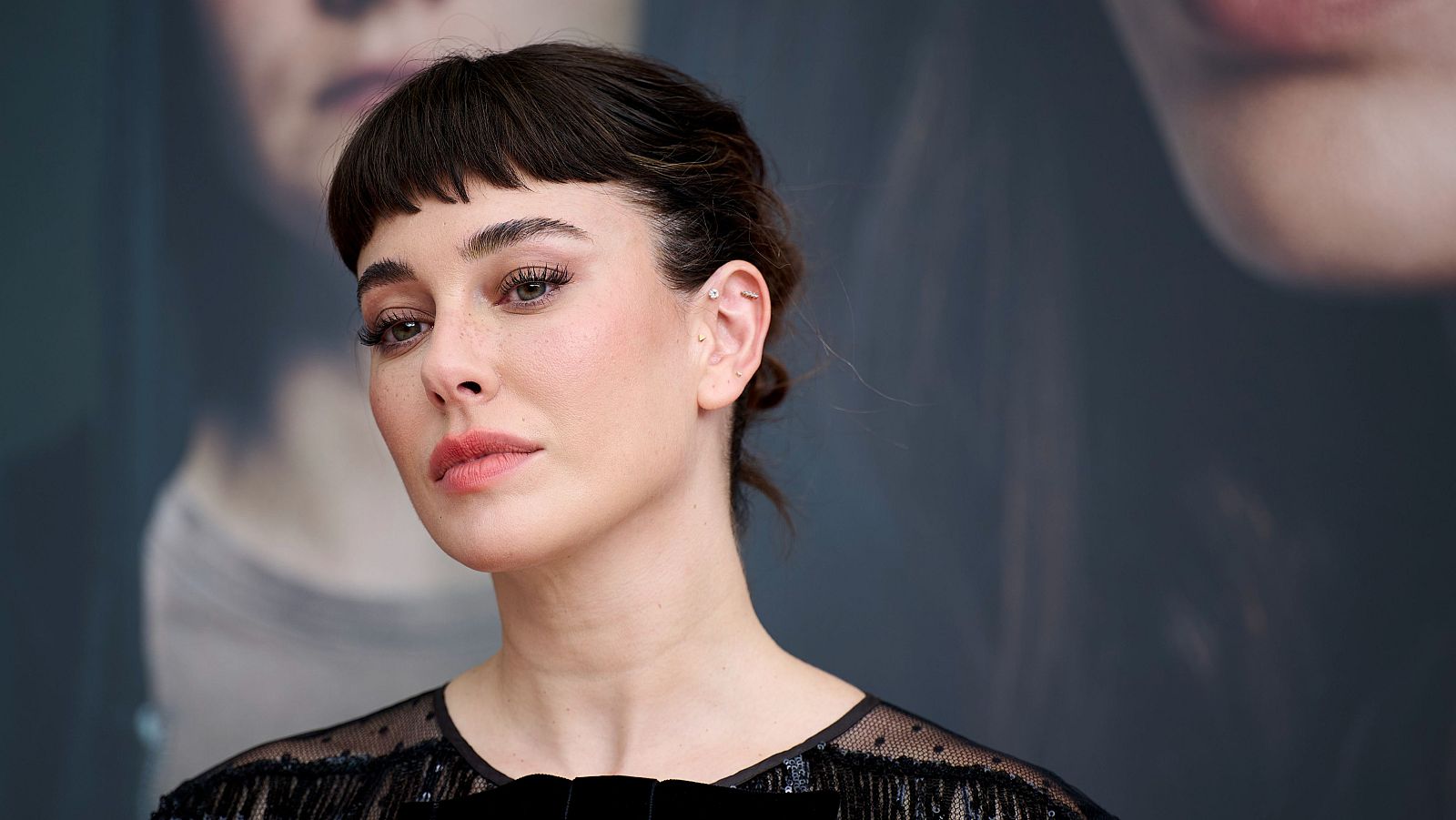 Retrato de Blanca Suárez con el pelo recogido, maquillaje discreto y pendientes pequeños; viste una blusa negra semitransparente.