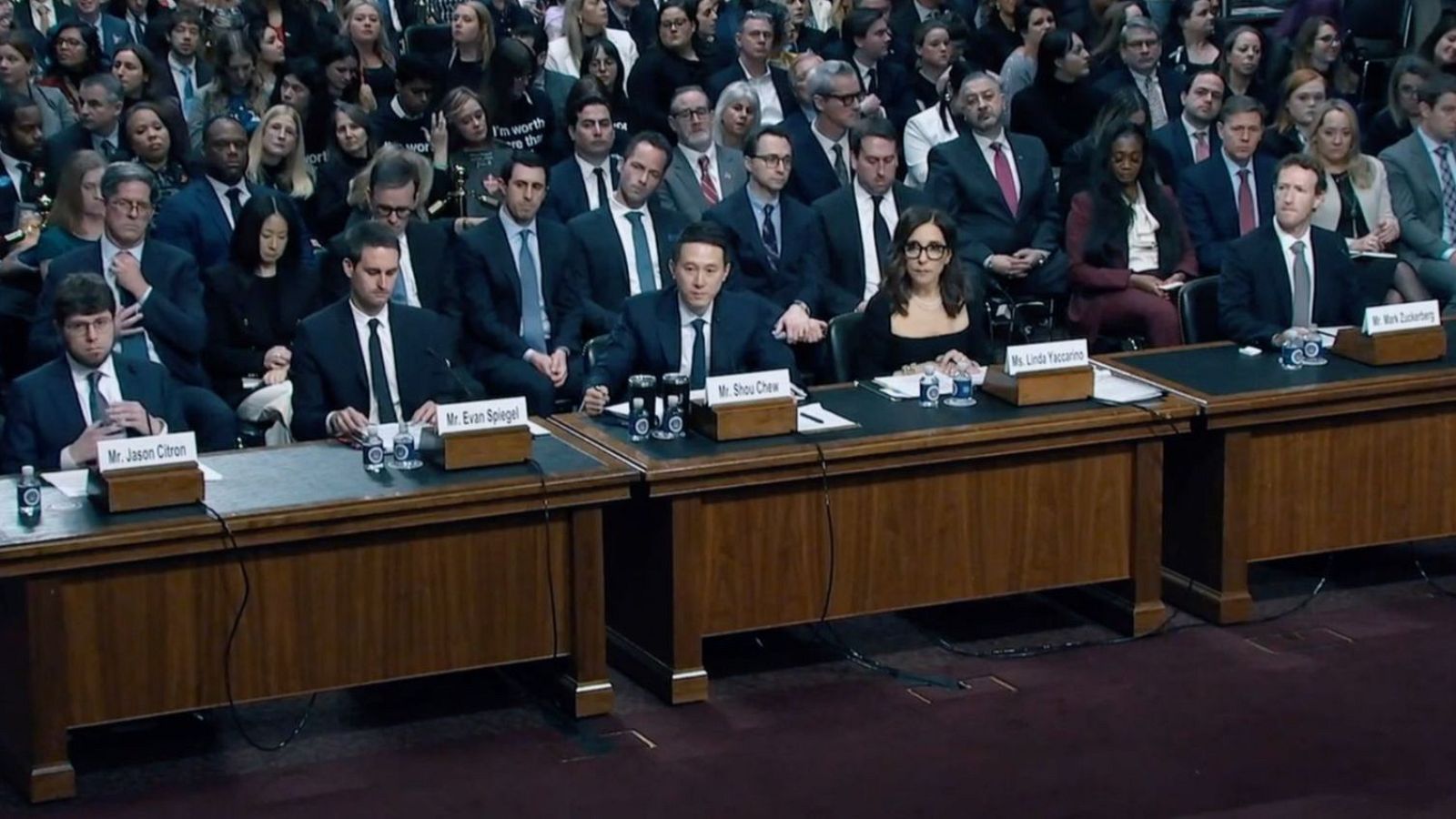 Directivos de empresas tecnológicas sentados en una mesa durante una audiencia pública, posiblemente sobre el impacto de las redes sociales.  Se observa a varios asistentes.