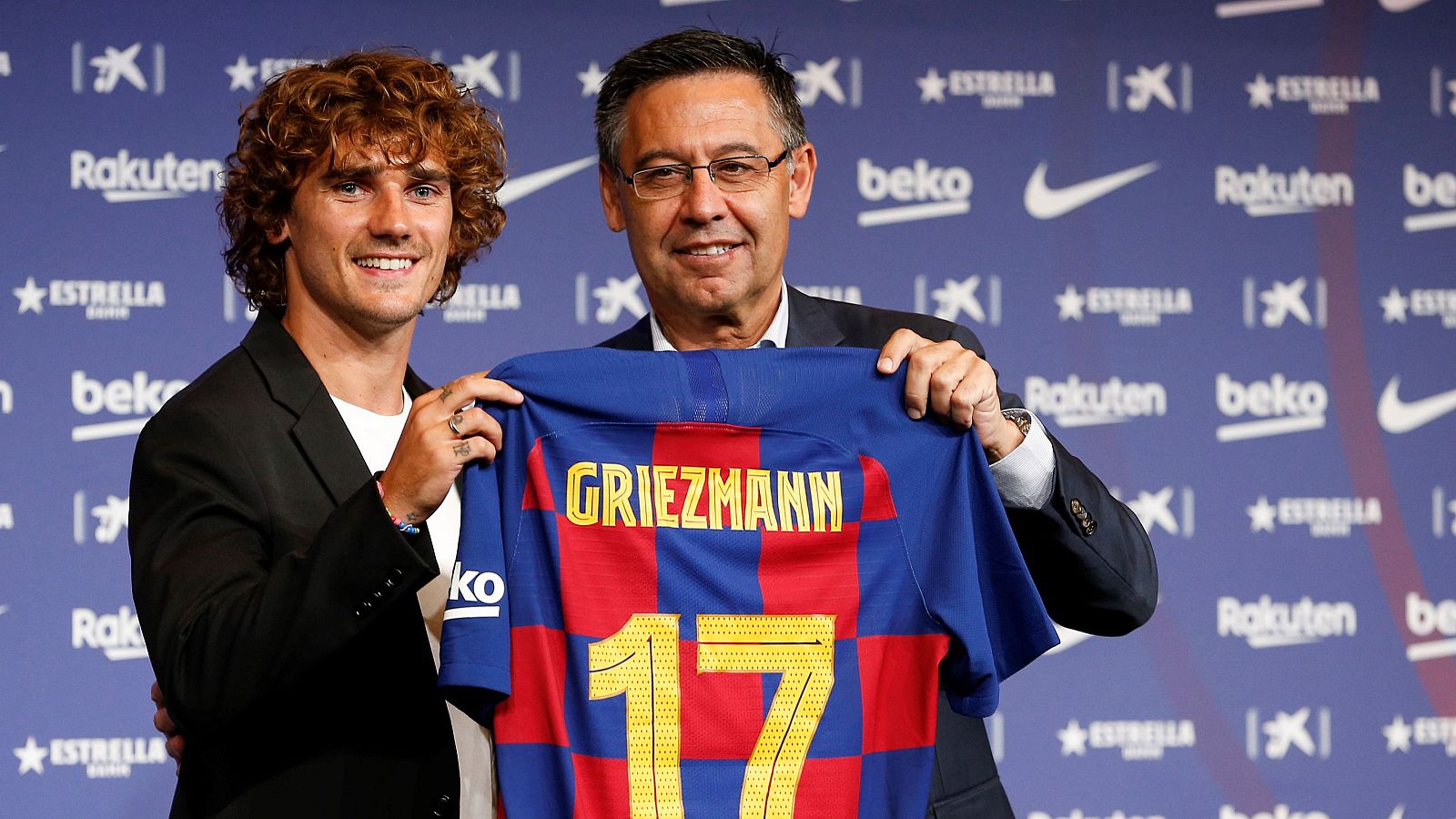El delantero francés Antoine Griezmann (i) posa para los medios de comunicación con el presidente del club, Josep Maria Bartomeu en el Camp Nou tras firmar como jugador del F.C. Barcelona.