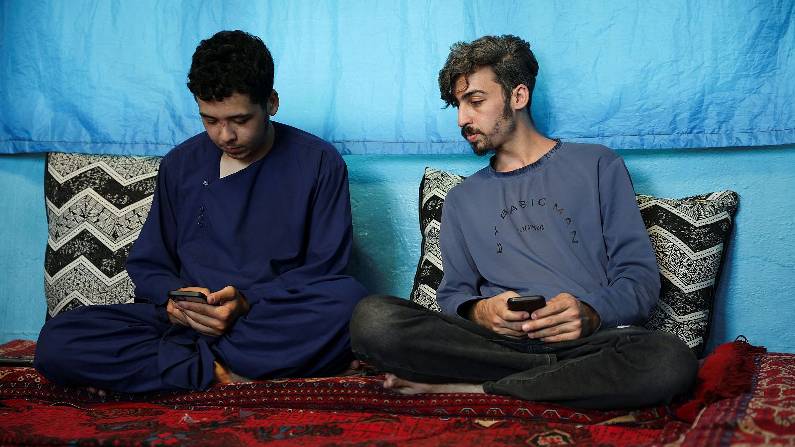 Dos jóvenes miran sus móviles en Kabul