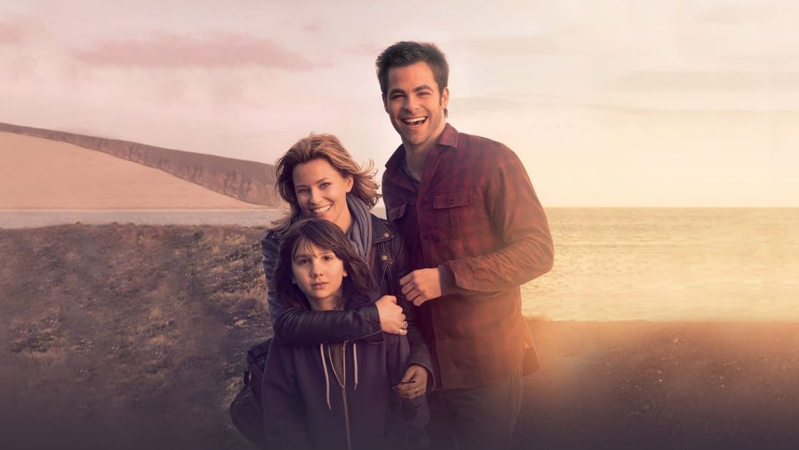 Una familia posa en un entorno natural; una mujer abraza a una niña, mientras un hombre sonríe a la cámara. El fondo muestra un paisaje costero con playa, mar y colinas, con un cielo iluminado.