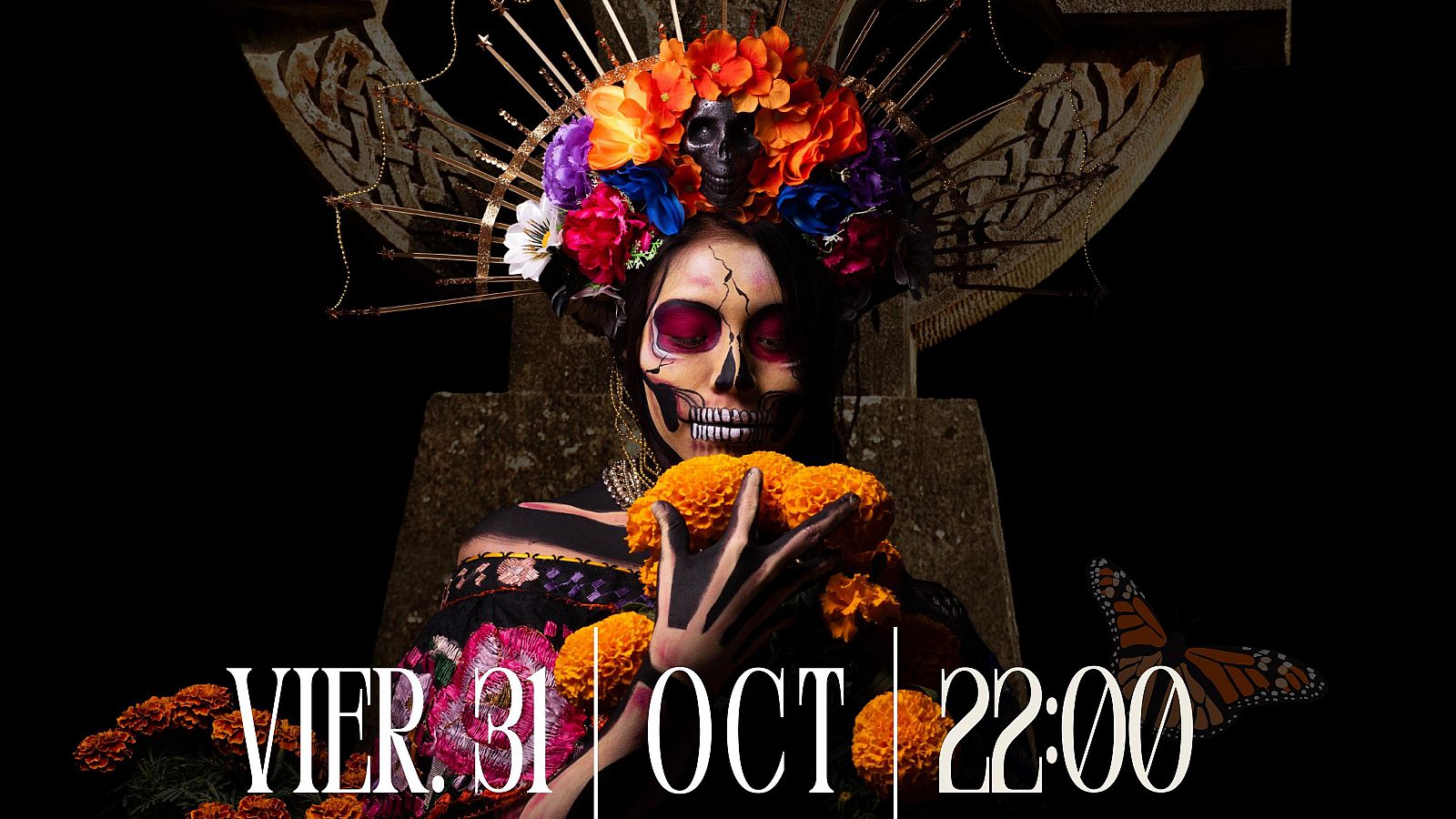 Una persona con maquillaje de calavera y un tocado floral, sosteniendo flores naranjas, posa frente a una cruz celta. En la parte inferior se lee una fecha y hora.