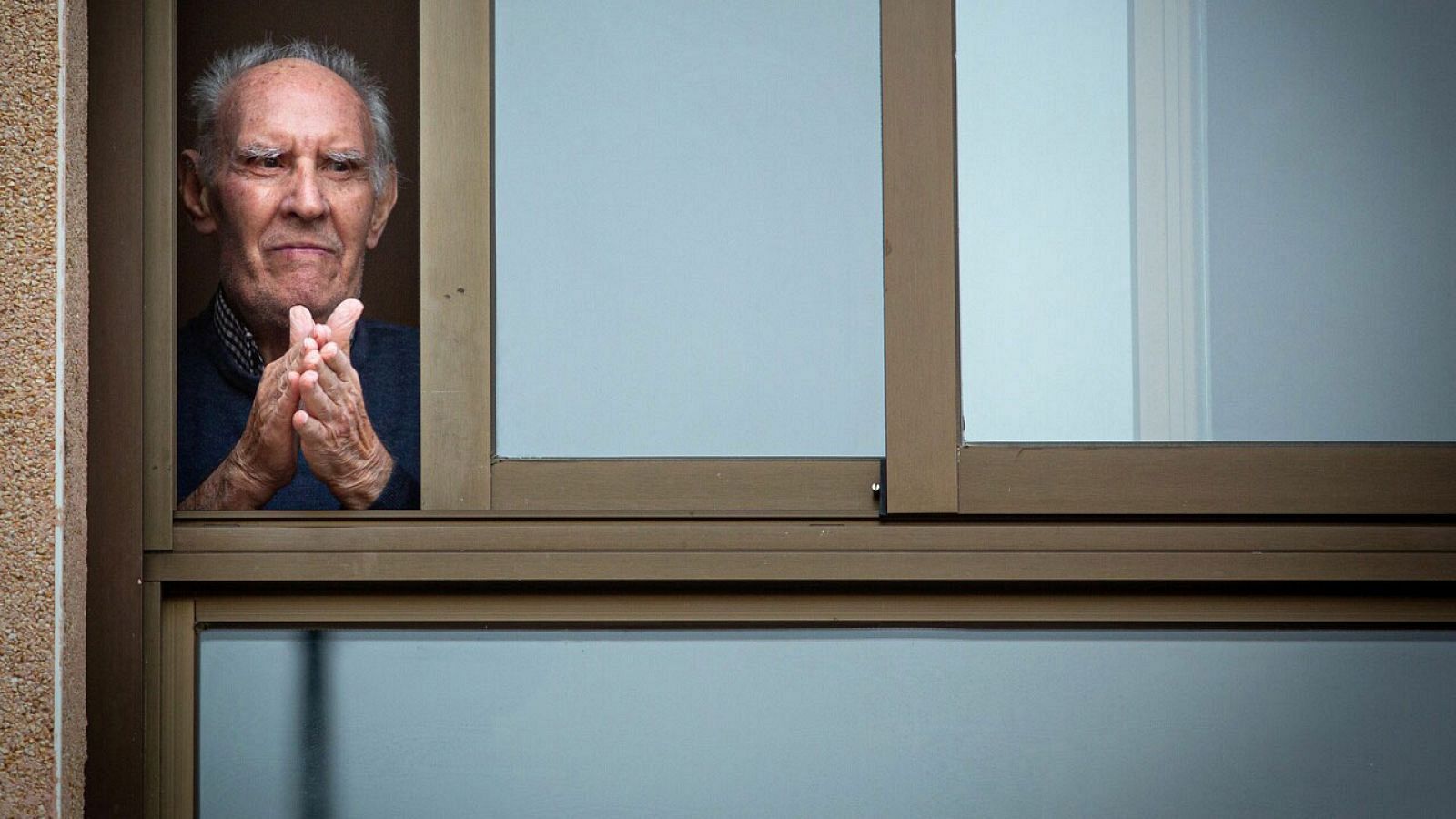 Un ancià observa l’exterior des de la finestra d'una residència