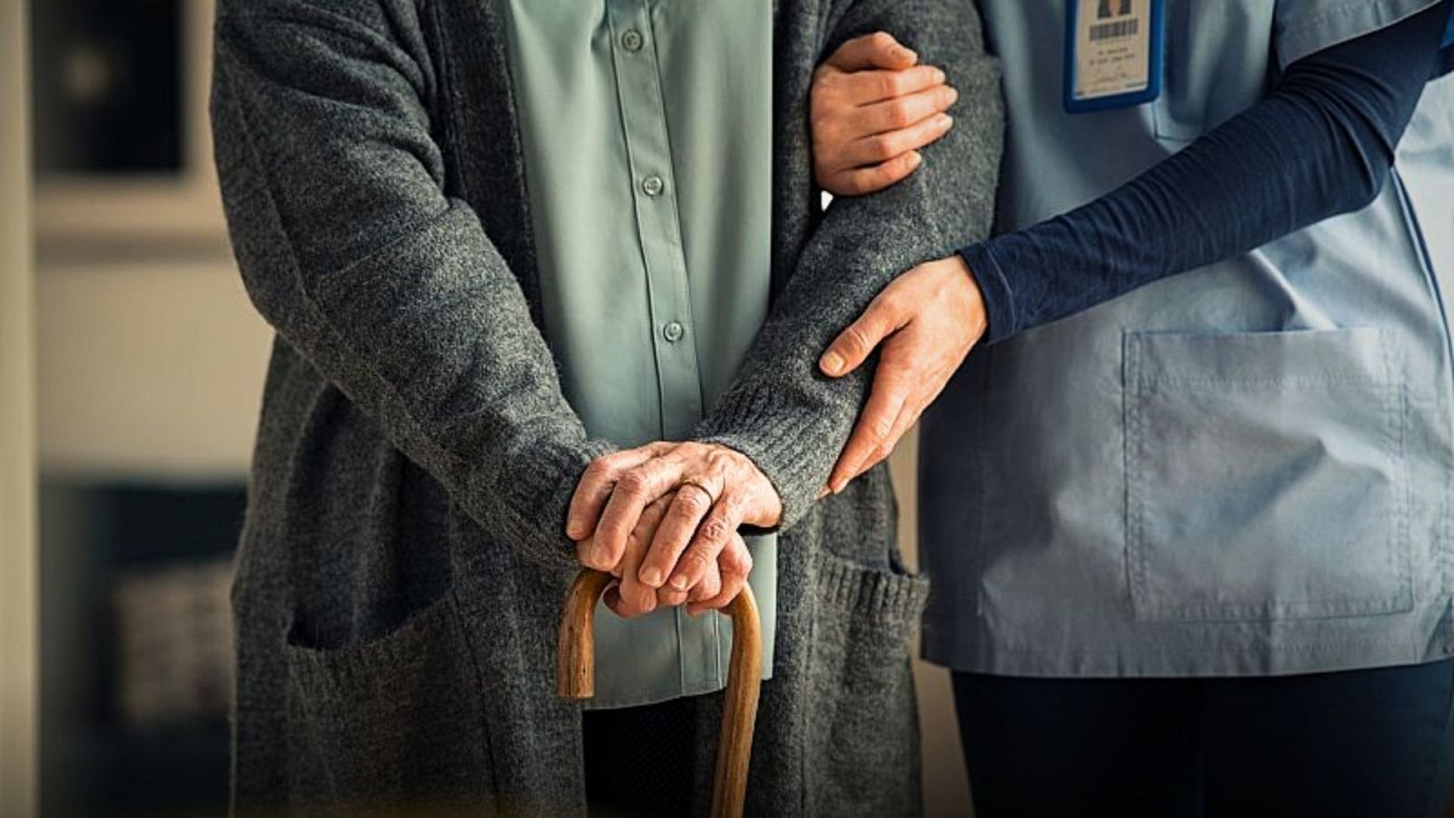 Imatge d'una persona gran assistida per un infermer en un centre residencial