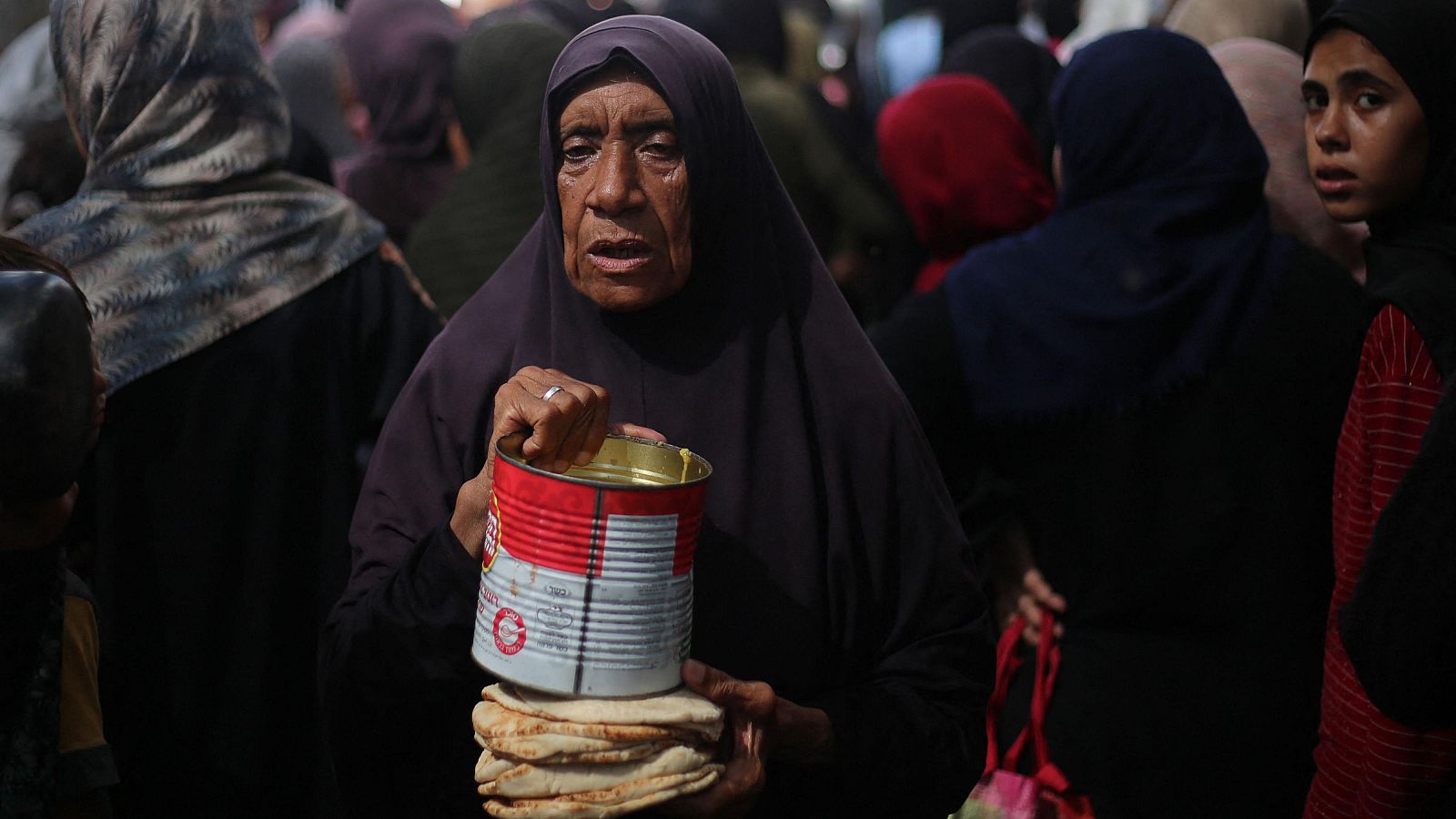 Una mujer desplazada se acerca para recibir raciones de comida de un comedor social en el campo de refugiados de Nuseirat.