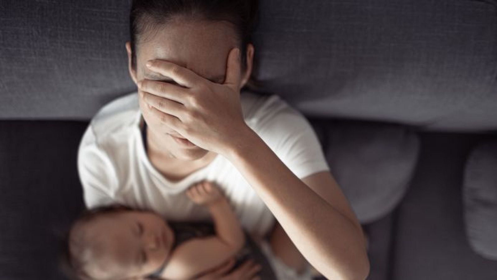 Madre superada con un bebé en brazos.
