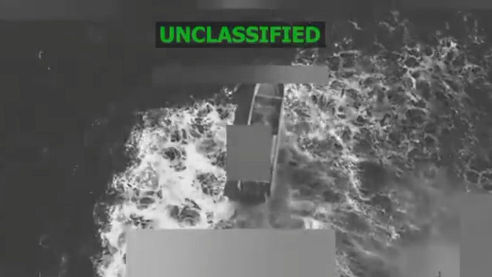 Imagen en blanco y negro de un buque en el mar, con olas alrededor y áreas censuradas, mostrando la palabra "UNCLASSIFIED" en la parte superior.